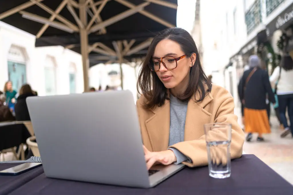 Woman working on remote from outdoor cafe
