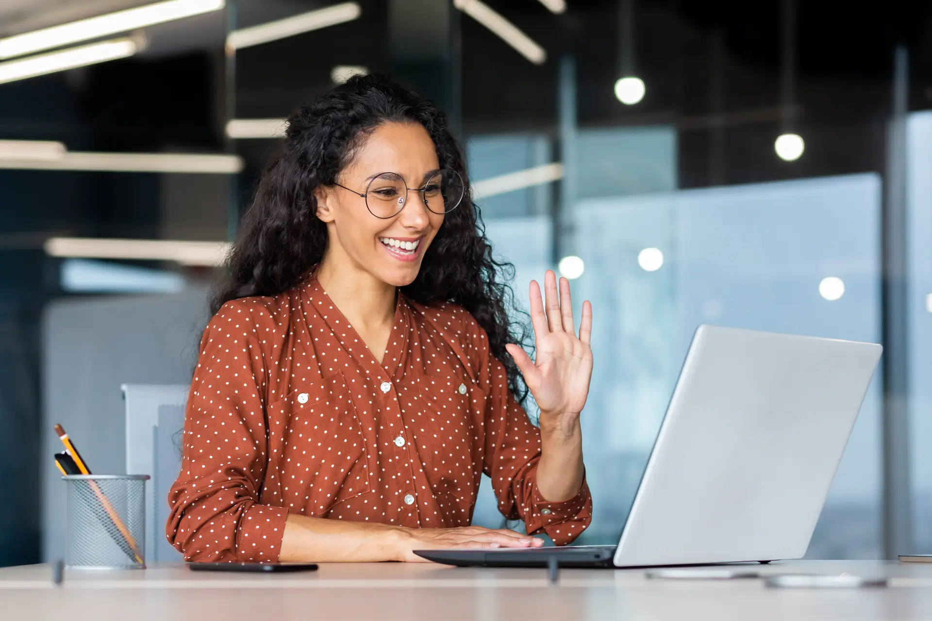 a spanish remote interpreter on her laptop waving at a client