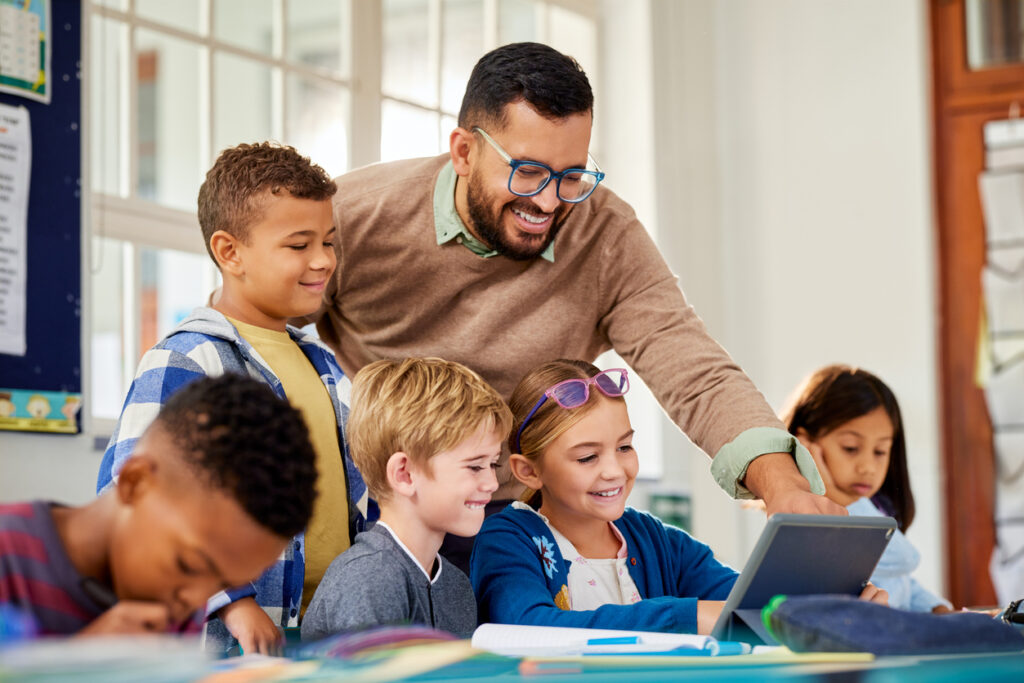 Primary multiethnic pupils working on digital tablet with teacher