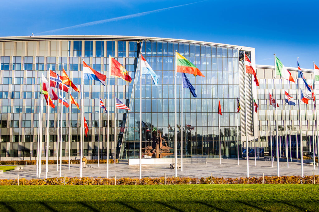 NATO building headquarters with flags and symbol outside
