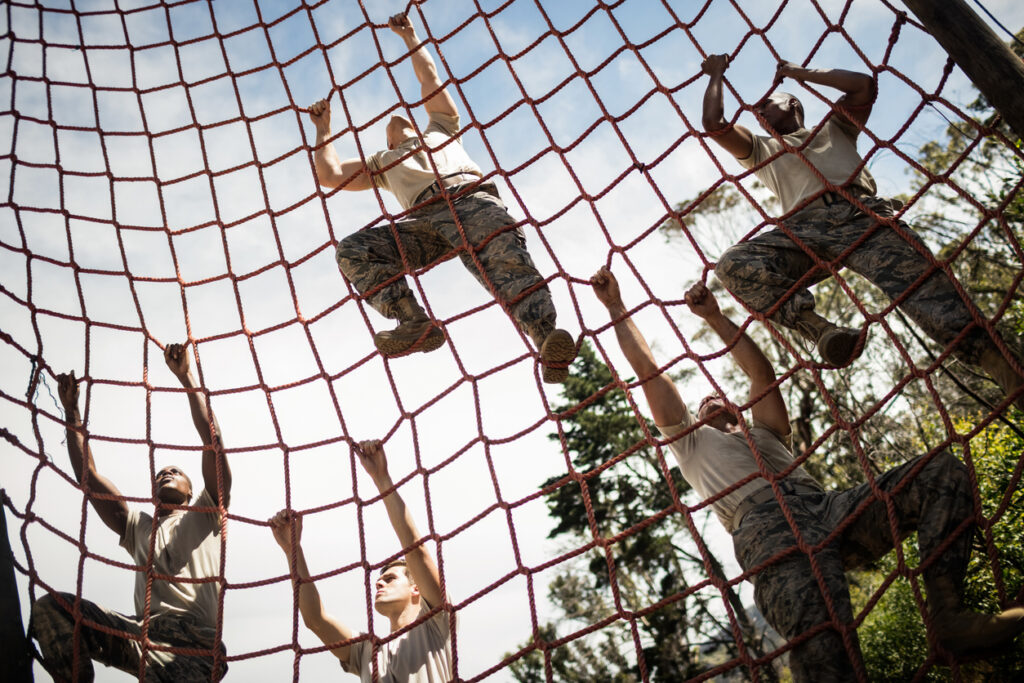 Military soldiers climbing rope during obstacle course